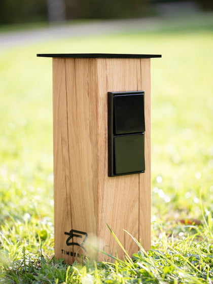 Steckdosensäule auf dem Rasen im Garten bei Sonnenschein. 