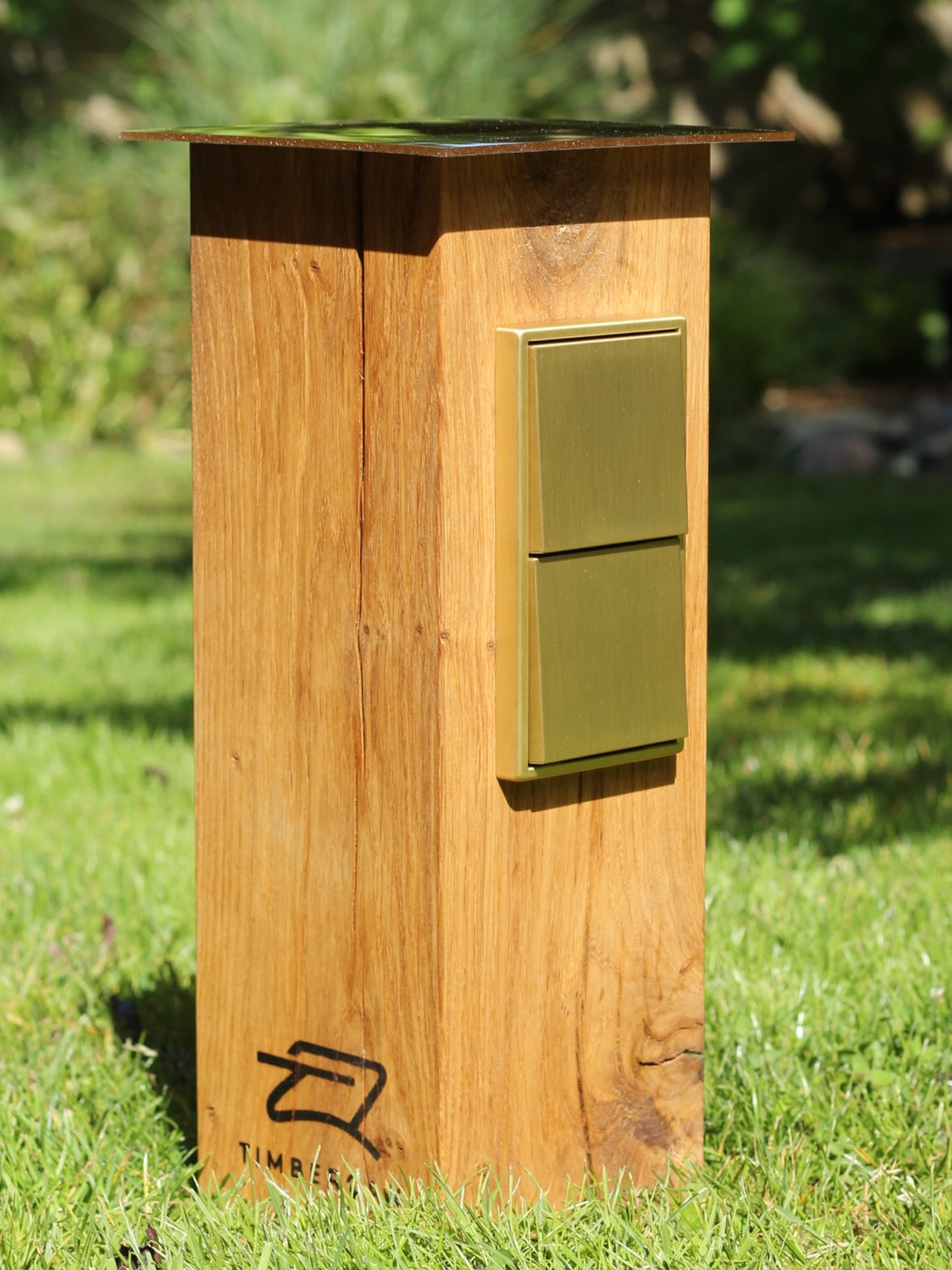 Goldene Steckdosensäule aus Holz von Timbercan im Außenbereich. 