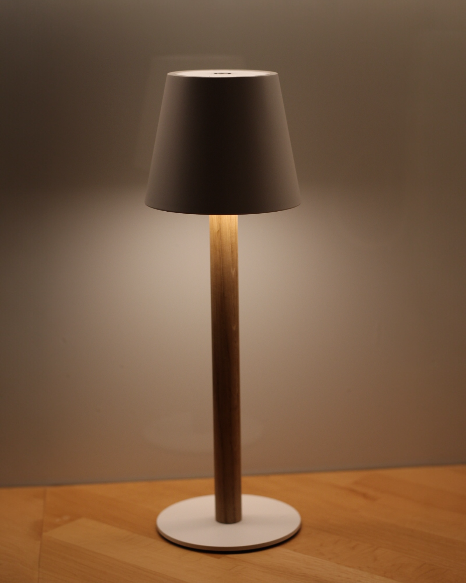 Beleuchtete weiße TIMBERCAN Akku-Tischlampe mit Eichenholz-Ständer auf Arbeitsplatte – dimmbare, kabellose LED-Designleuchte