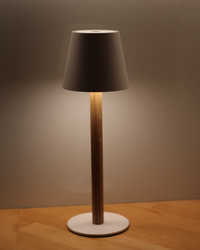 Beleuchtete weiße TIMBERCAN Akku-Tischlampe mit Eichenholz-Ständer auf Arbeitsplatte – dimmbare, kabellose LED-Designleuchte